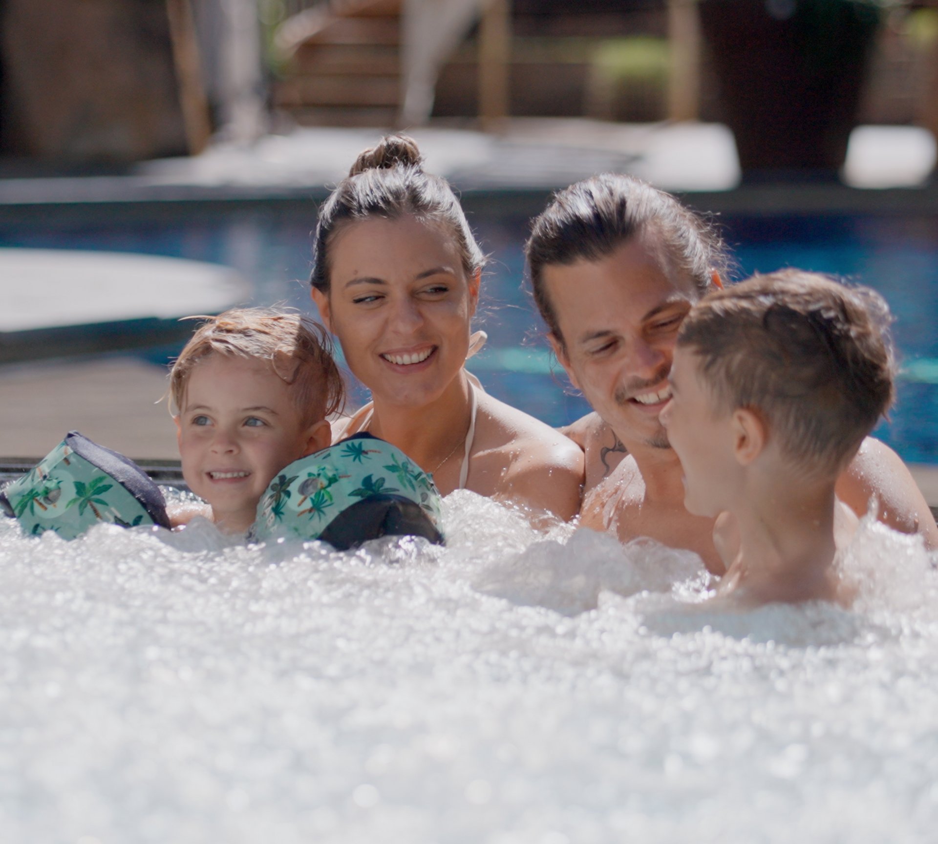 TYROL Family Retreat als Familienhotels in Südtirol Familie mit zwei Kindern entspannt im Whirlpool am Pool