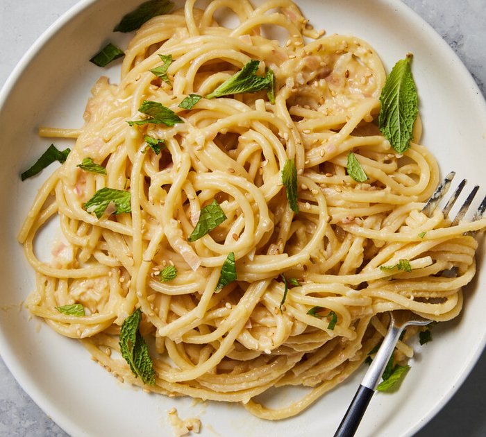 Pure Flexibilität im TYROL Family Retreat Spaghetti mit cremiger Sauce, garniert mit frischen Minzblättern auf weißem Teller
