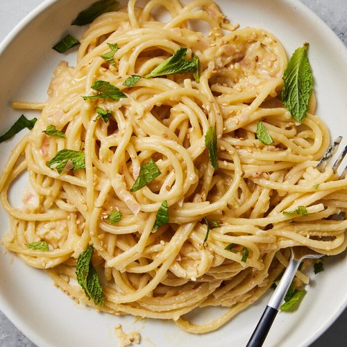 Pure Flexibilität im TYROL Family Retreat Spaghetti mit cremiger Sauce, garniert mit frischen Minzblättern auf weißem Teller