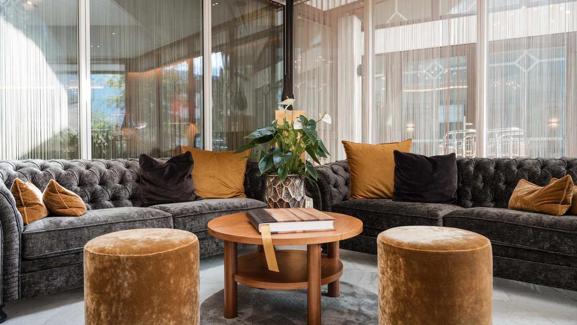 TYROL Family Retreat als Familienhotels in Südtirol Moderne gemütliche Sitzecke mit zwei Sofas, Hockern und runden Holztisch