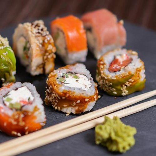 Pure Flexibilität im TYROL Family Retreat Verschiedene Sushi-Rollen mit Wasabi und Essstäbchen auf schwarzem Teller