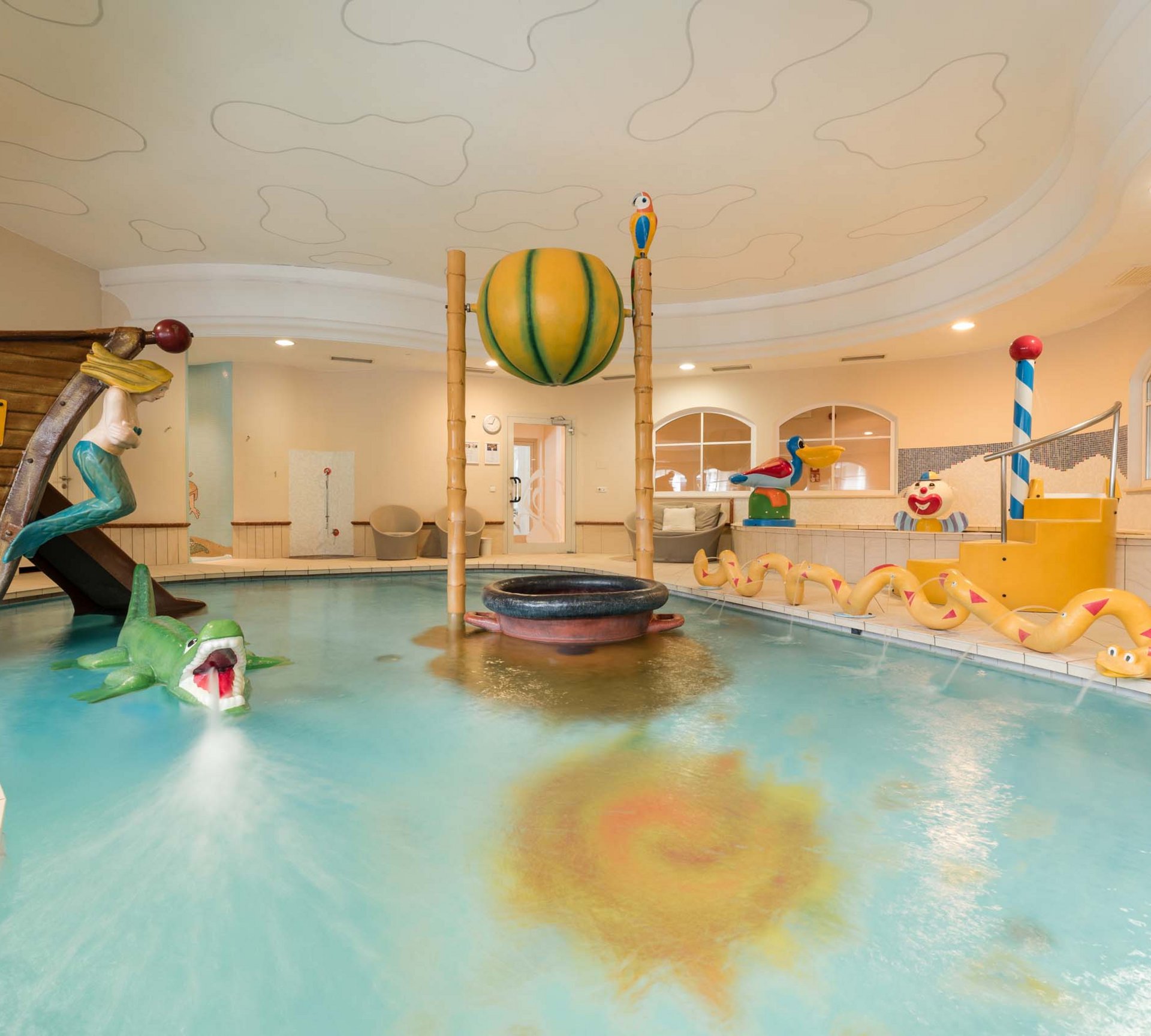 Euer Urlaub im Babyhotel in Südtirol Innenkinderpool mit Bootsrutsche und Wasserspielzeug in gelbem Raum