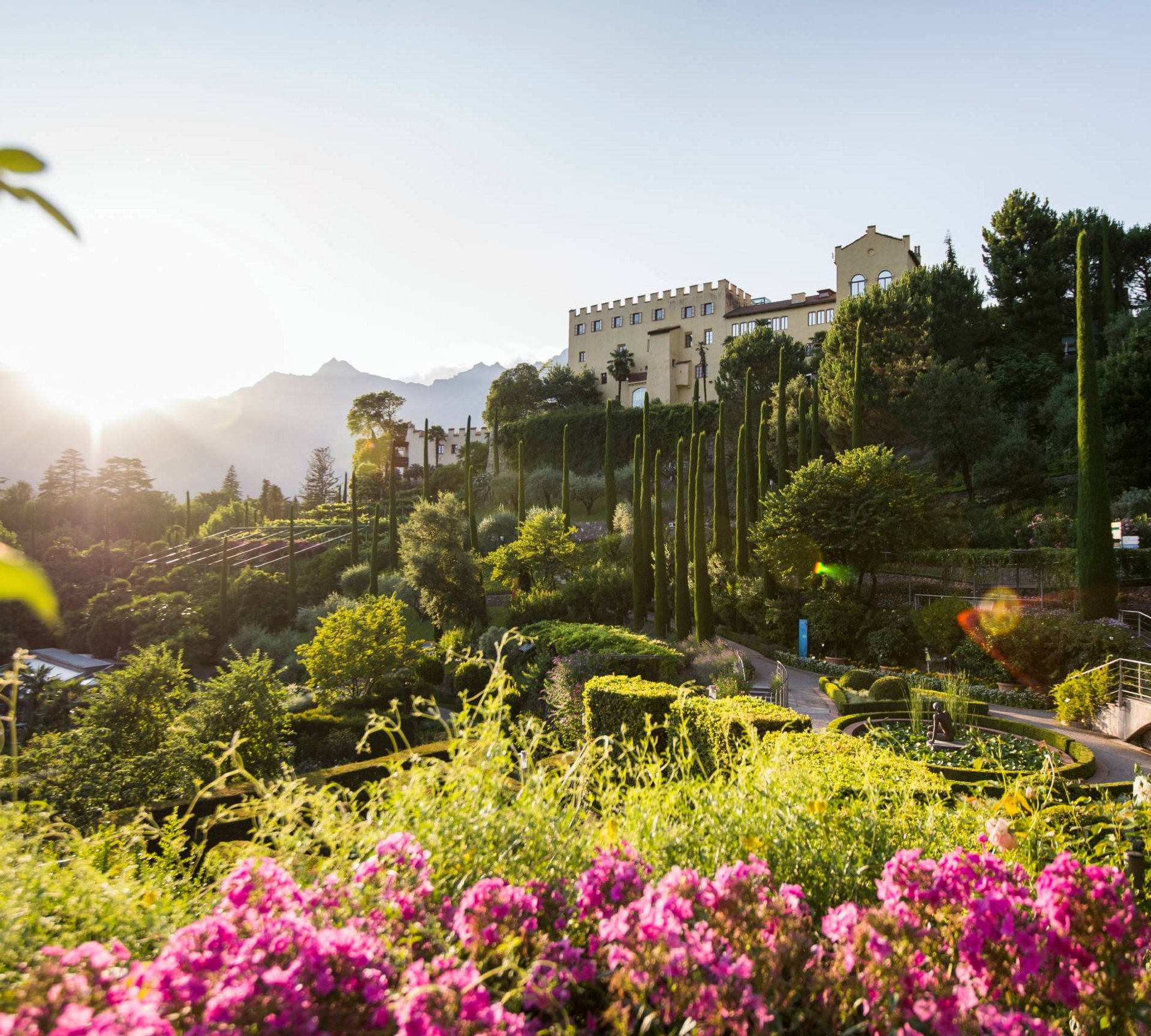 Langeweile ade im Aktivhotel in Südtirol Schloss mit Garten, hohen Zypressen und Sonnenuntergang in den Bergen