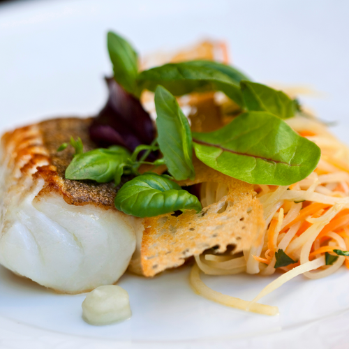 Rusterkeller Gebratenes Fischfilet mit frischen Kräutern und Gemüsesalat auf weißem Teller