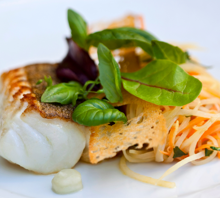 Rusterkeller Gebratenes Fischfilet mit frischen Kräutern und Gemüsesalat auf weißem Teller