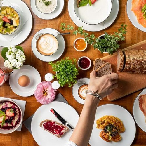 Pure Flexibilität im TYROL Family Retreat Frühstückstisch mit Brot, Eiern, Aufschnitt, Gemüse und Kaffee