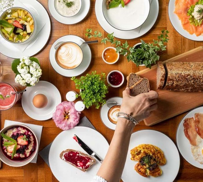 Pure Flexibilität im TYROL Family Retreat Frühstückstisch mit Brot, Eiern, Aufschnitt, Gemüse und Kaffee