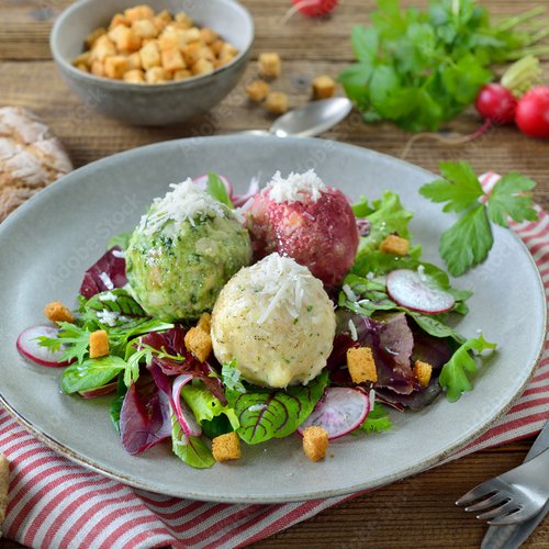 Pure Flexibilität im TYROL Family Retreat Drei bunte Knödel auf gemischtem Blattsalat mit Croutons auf Teller
