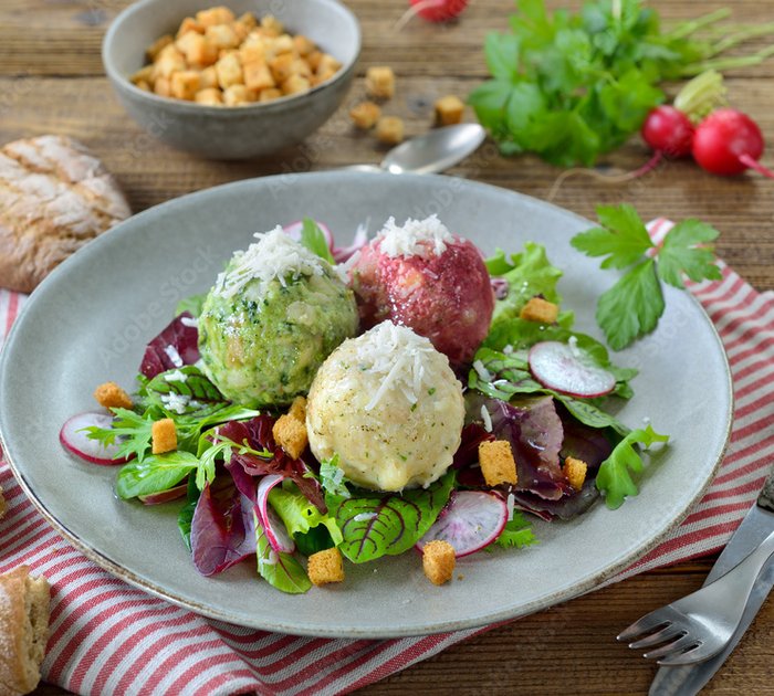 Pure Flexibilität im TYROL Family Retreat Drei bunte Knödel auf gemischtem Blattsalat mit Croutons auf Teller