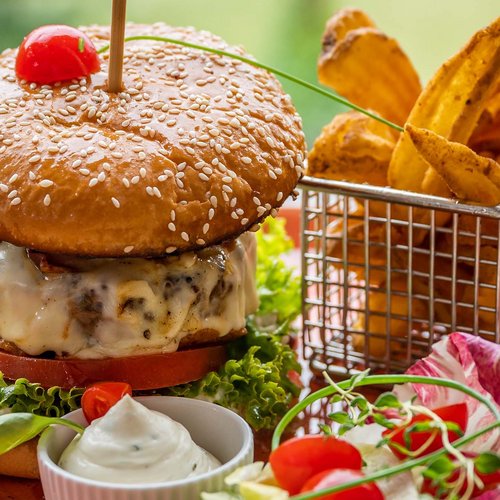 Pure Flexibilität im TYROL Family Retreat Hamburger mit Käse, Salat, Pommes und Dips auf einem Teller