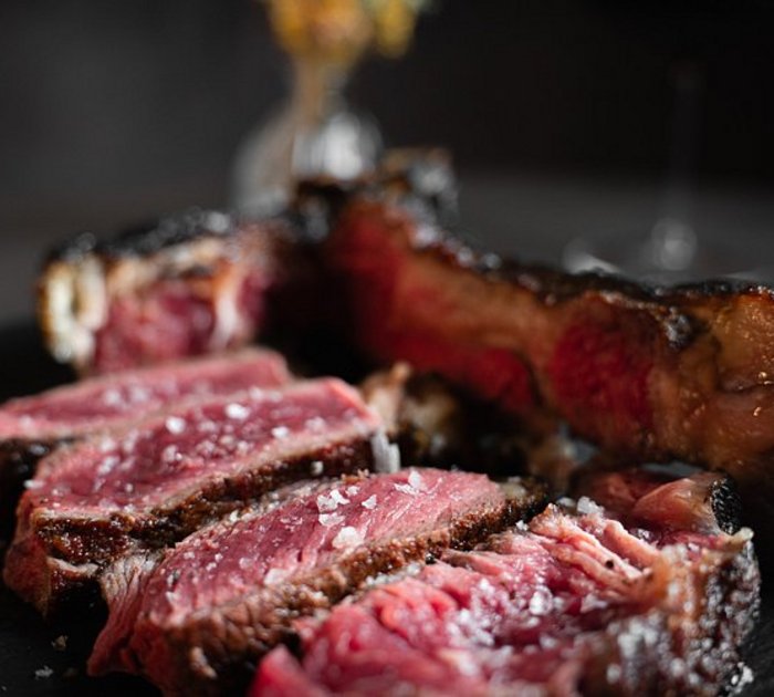 Pure Flexibilität im TYROL Family Retreat Nahaufnahme von in Scheiben geschnittenem rosa, saftigem Steak auf dunklem Teller