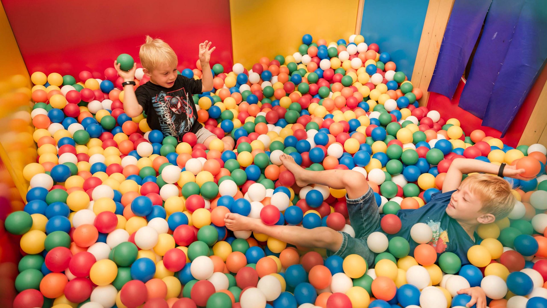 TYROL Family Retreat als Familienhotels in Südtirol Zwei Jungen spielen in einem Bällebad mit bunten Kunststoffbällen