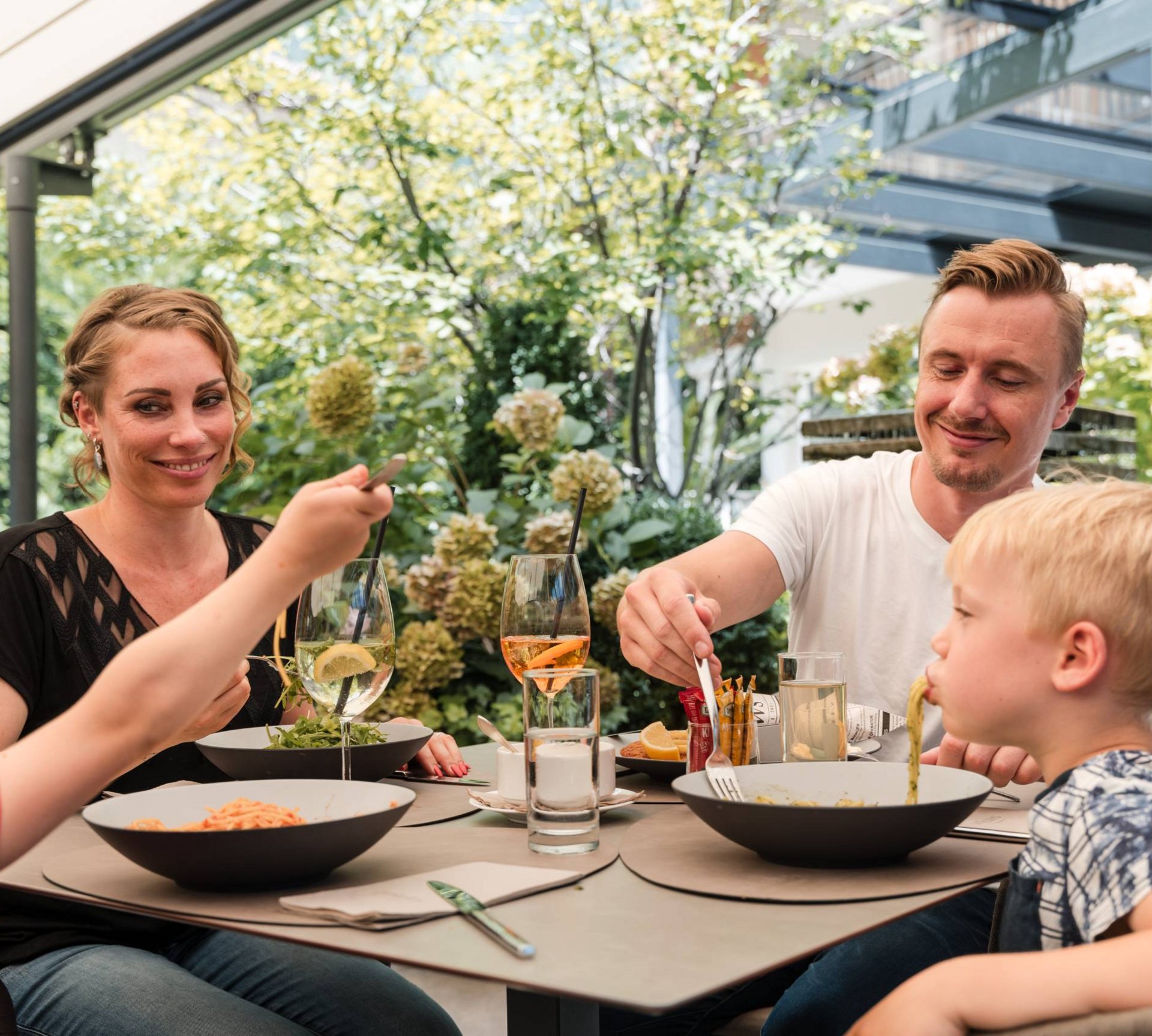 Pure Flexibilität im TYROL Family Retreat Familie mit zwei Kindern beim gemeinsamen Essen im Garten