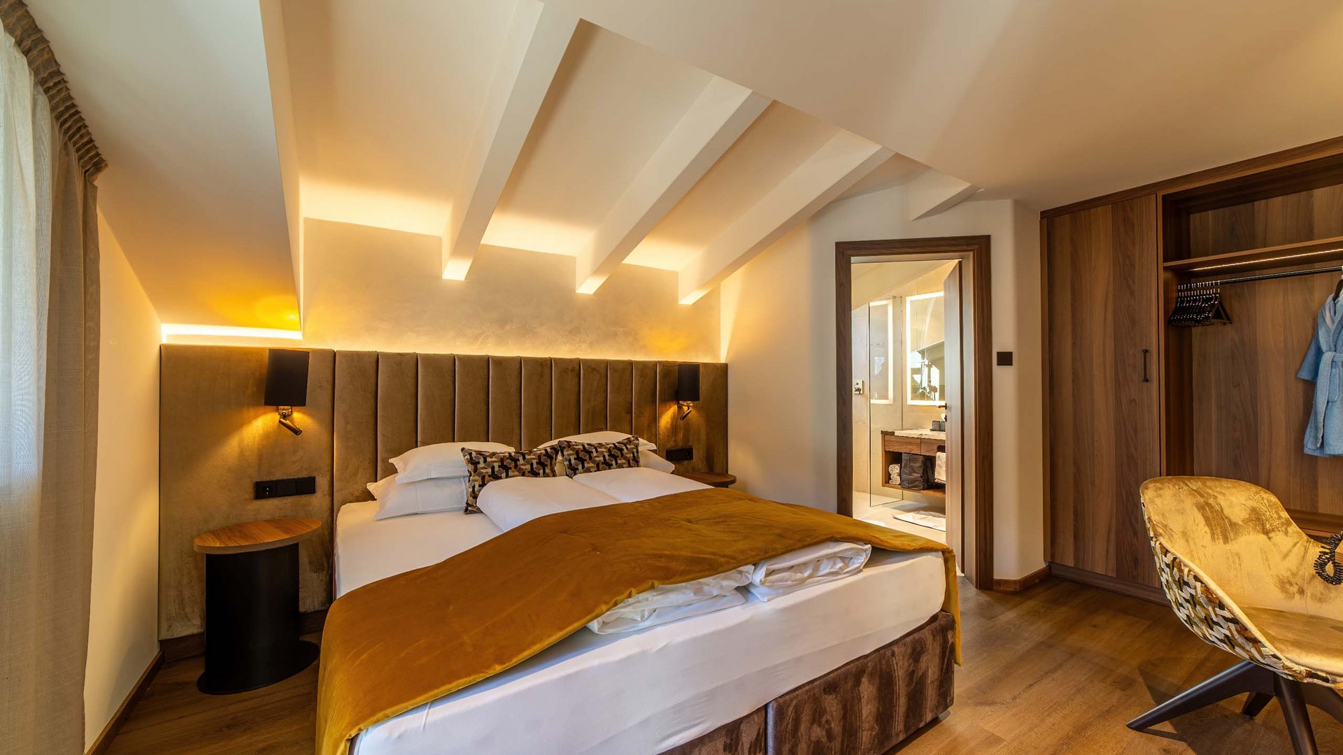 TYROL Family Retreat als Familienhotels in Südtirol Gemütliches Schlafzimmer mit Doppelbett, indirekter Beleuchtung und offenem Bad
