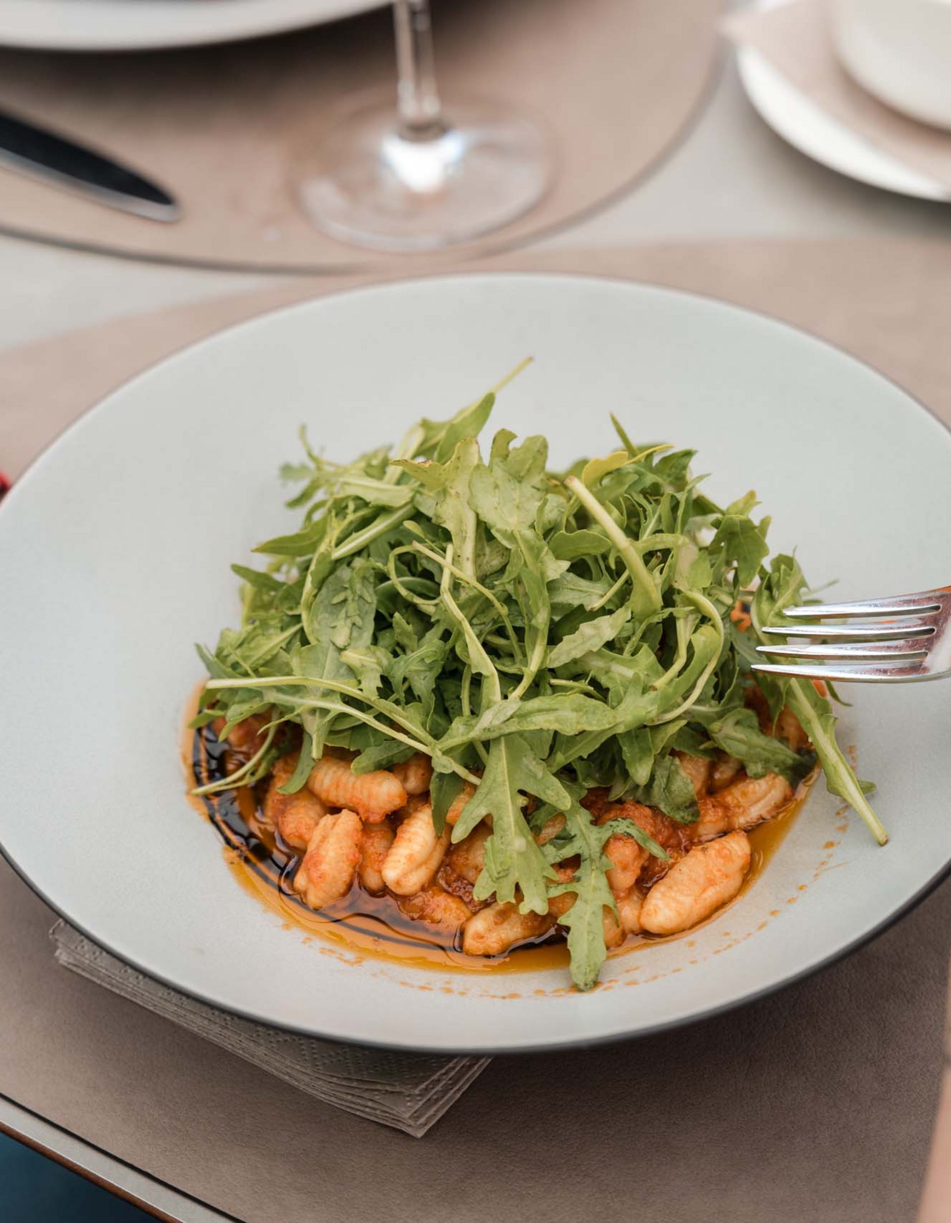 TYROL Family Retreat. Mehr als ein Familienhotel in Naturns. Gnocchi mit Rucola und Balsamico in einem weißen Teller