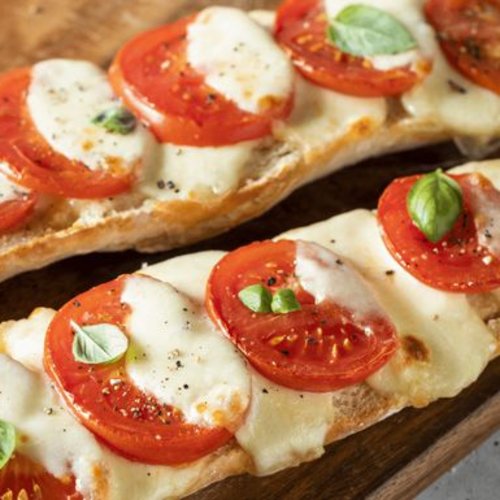 Pure Flexibilität im TYROL Family Retreat Baguette mit Tomaten, Mozzarella und Basilikum auf Holzbrett