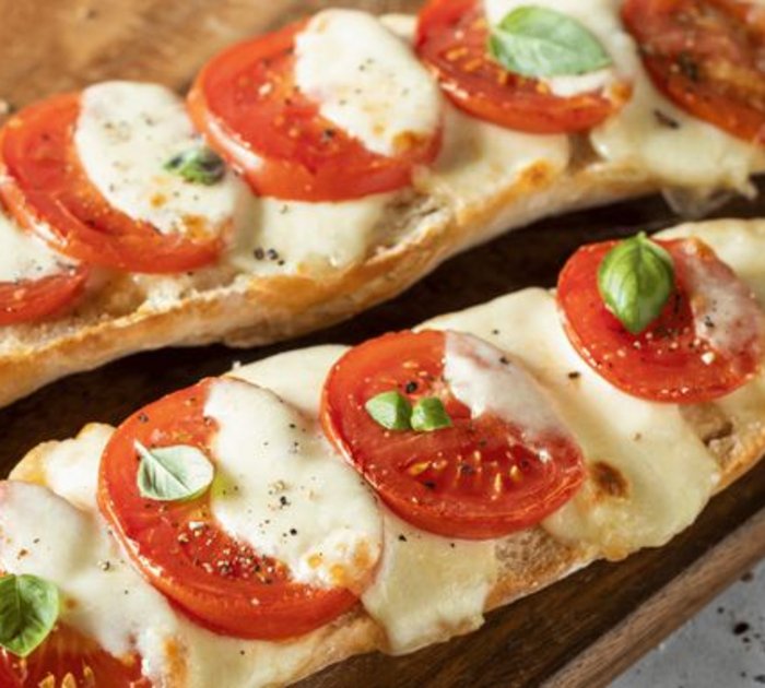 Pure Flexibilität im TYROL Family Retreat Baguette mit Tomaten, Mozzarella und Basilikum auf Holzbrett