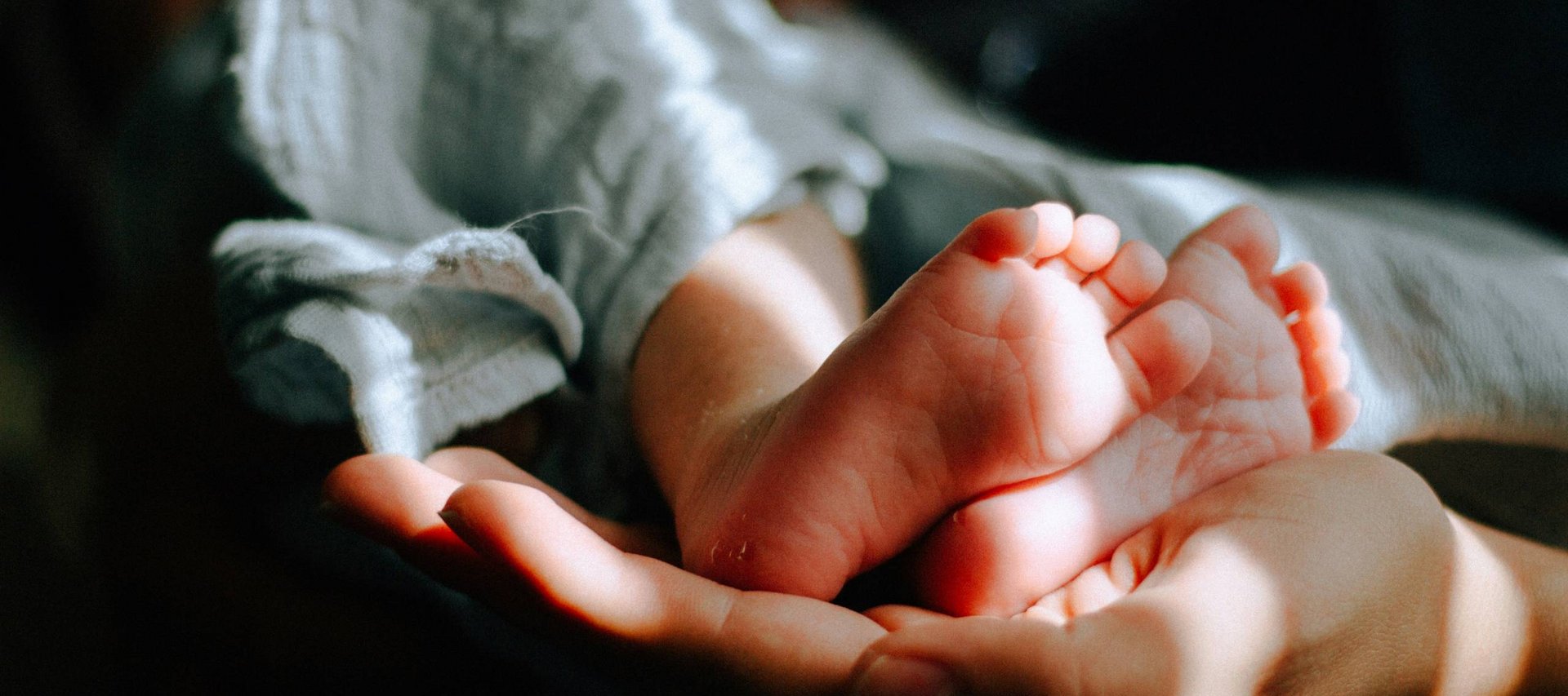 Euer Urlaub im Babyhotel in Südtirol Babyfüße werden von einer Hand sanft gehalten