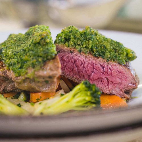 Pure Flexibilität im TYROL Family Retreat Saftiges Steak mit grüner Kräuterkruste und Gemüse auf weißem Teller
