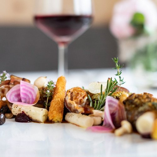 Pure Flexibilität im TYROL Family Retreat Gourmet-Gemüseplatte mit frischen Kräutern und Rotwein im Hintergrund