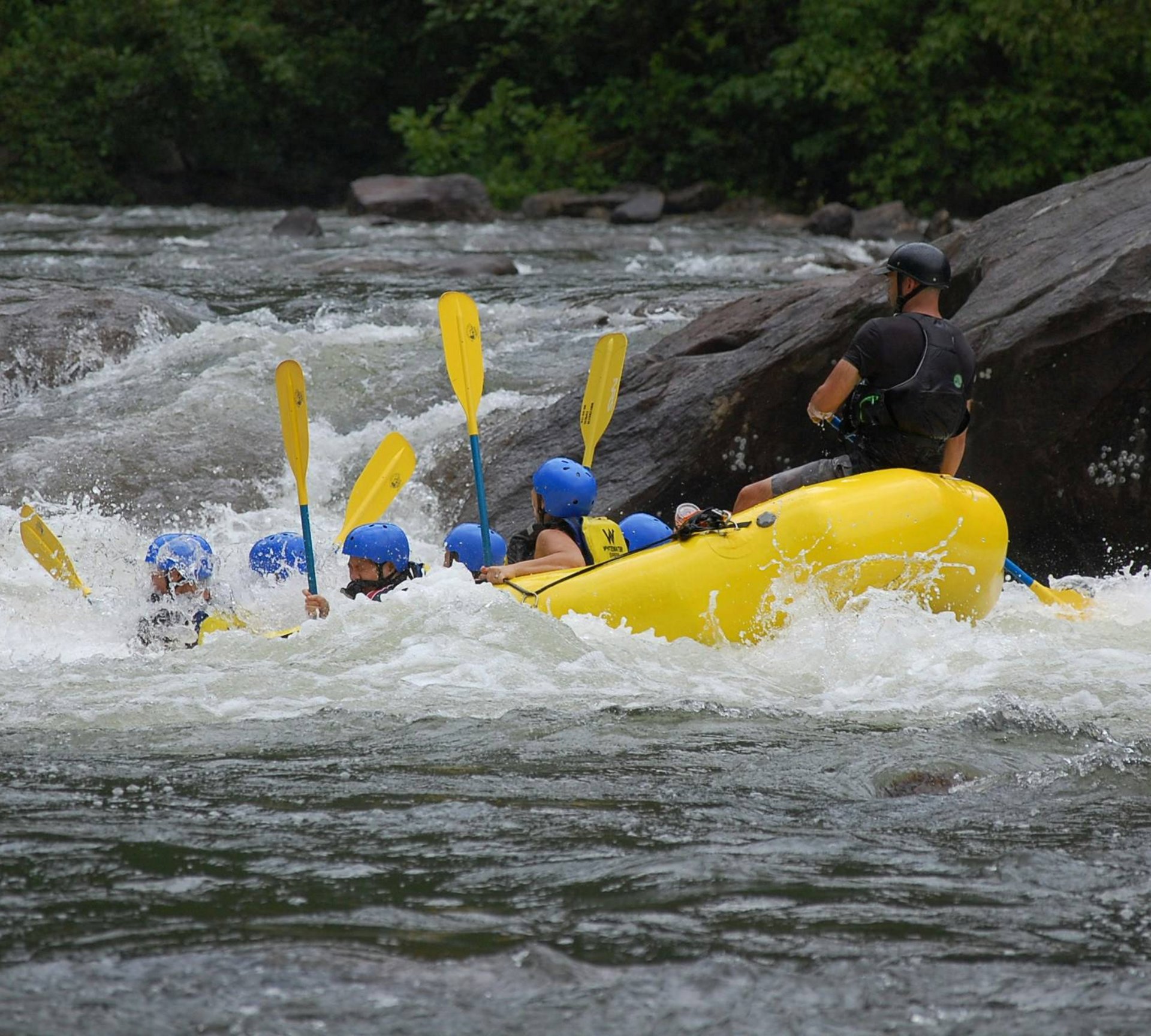 Abenteuer im Teenager-Hotel in Südtirol Gruppe beim Wildwasser-Rafting auf einem Fluss mit Helmen und Paddeln
