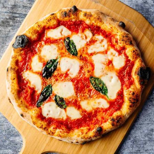 Pure Flexibilität im TYROL Family Retreat Pizza Margherita mit Tomatensoße, Mozzarella und Basilikum auf Holzbrett
