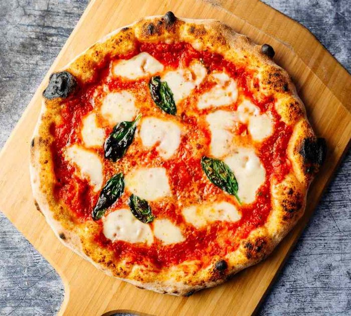 Pure Flexibilität im TYROL Family Retreat Pizza Margherita mit Tomatensoße, Mozzarella und Basilikum auf Holzbrett