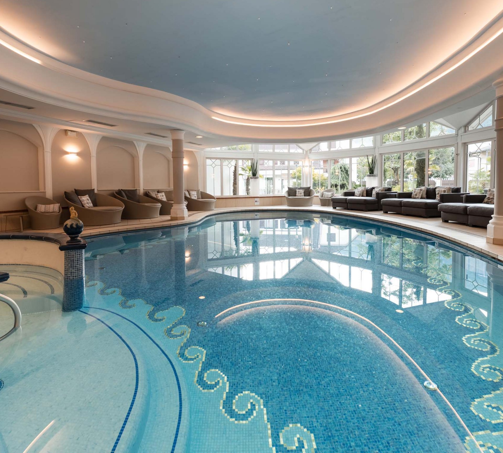Erholung im Wellnesshotel in Naturns Hallenbad mit Lounge-Bereich und großen Fenstern mit Blick ins Freie