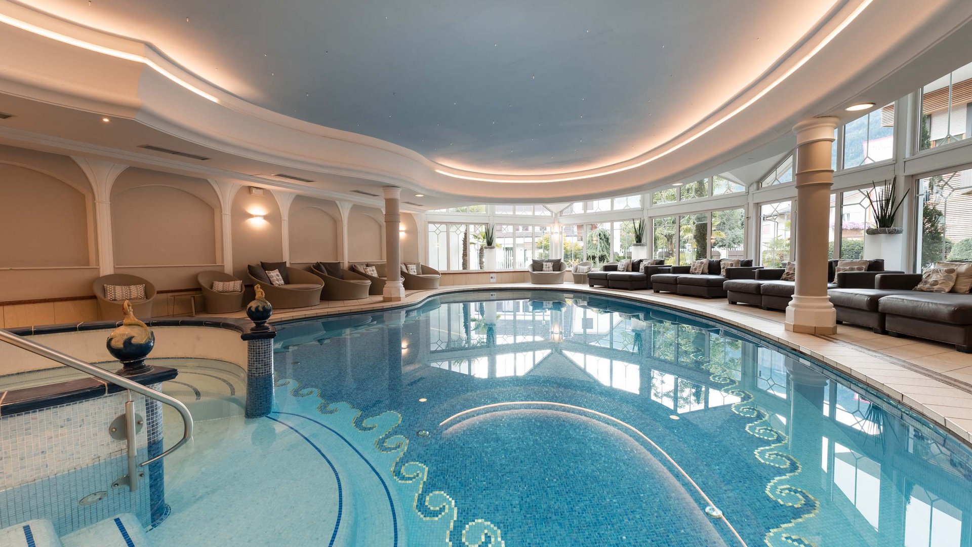 TYROL Family Retreat als Familienhotels in Südtirol Hallenbad mit Lounge-Bereich und großen Fenstern mit Blick ins Freie