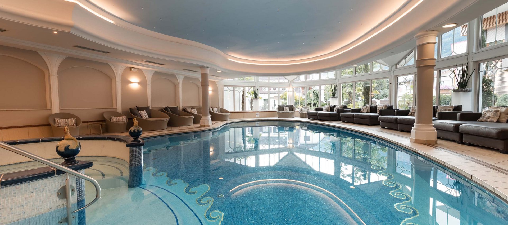 Königlicher Wasserspaß im Familienhotel in Naturns mit Pool Hallenbad mit Lounge-Bereich und großen Fenstern mit Blick ins Freie