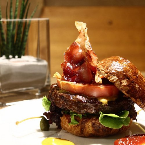 Pure Flexibilität im TYROL Family Retreat Hamburger mit Speck, Tomate, Salat und Soßen auf einem weißen Teller